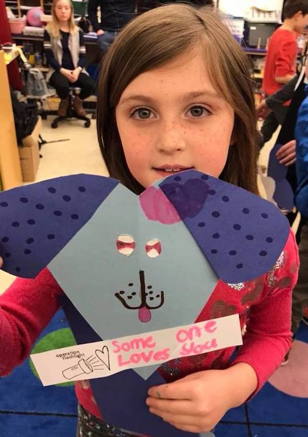 A Grace McWayne elementary student with a valentine that she created for Operation Flashlight.