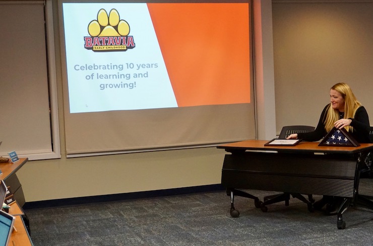 <p>EC Assistant Principal Jennifer Seaton celebrating the EC’s 10th Anniversary and showing Board Members the American Flag gifted to the EC by the United States Army.</p>
