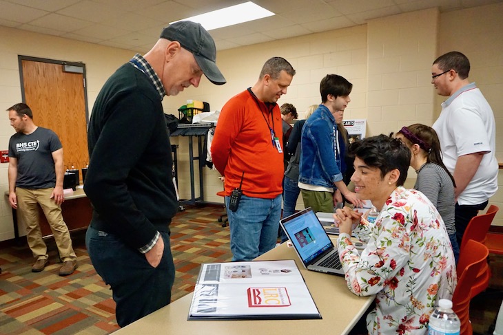 <p>Guest Christopher Cudworth, City of Batavia communications coordinator (far left), reviewing a student’s portfolio.</p>
