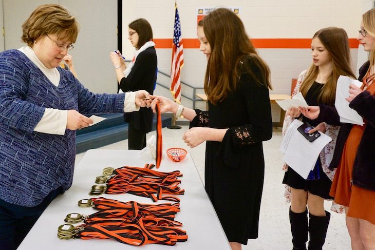 <p>After performing and getting scored by a judge, student musicians gave their score sheet to voluteers at the awards table to pick up their medals. </p>
